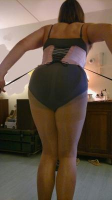 Sissy en pantimedias, corsé y tacones rojos.